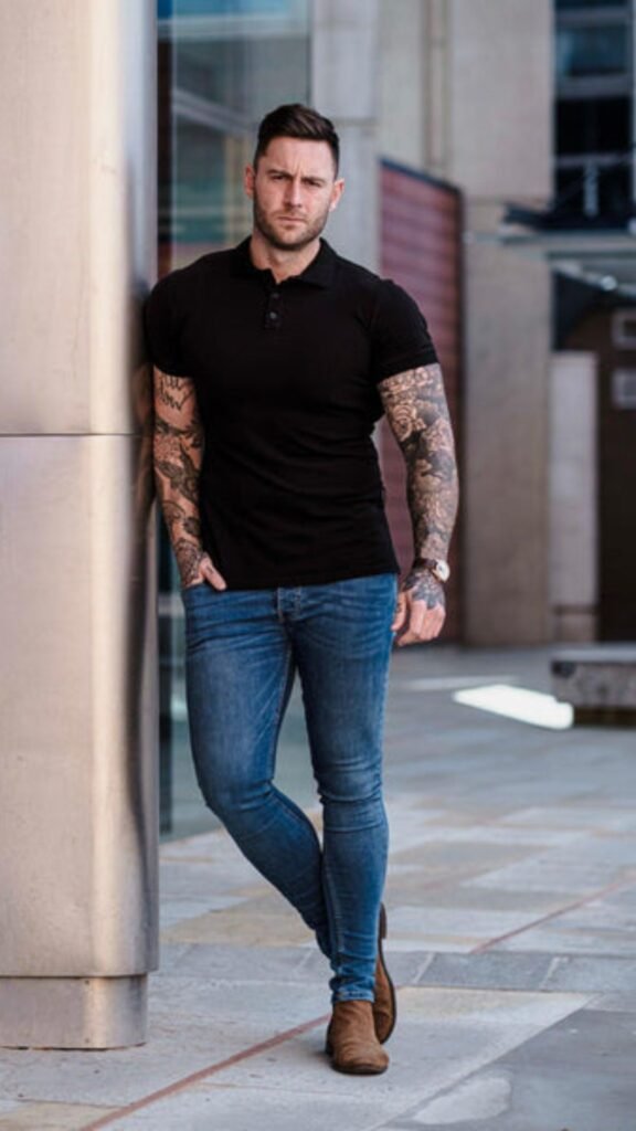 a man with tattoos on his arm leaning against a wall
